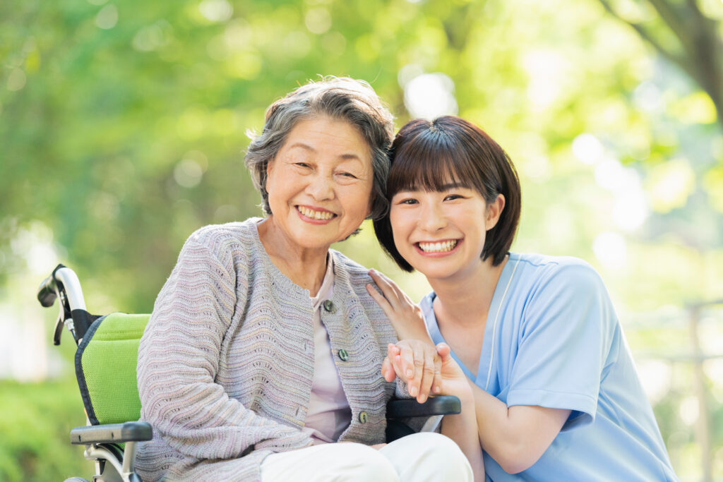 屋外で笑顔を見せる高齢の女性と支援者