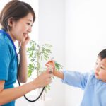 子どもを診察する若い看護師
